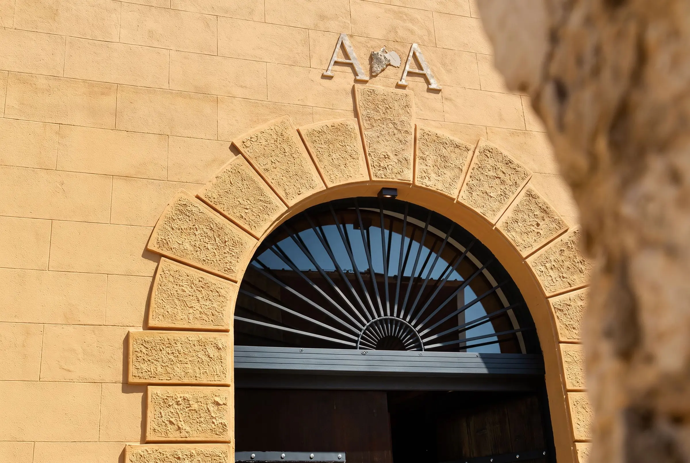 La facciata di Antiche Cantine in via Madonna del Riposo ad Alcamo, il portone ad arco e il monogramma inciso nella pietra